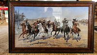 Full view of the framed art print showing a group of cowboys on horses riding through a dusty landscape.