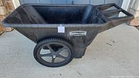 Side view of large black Rubbermaid resin wheelbarrow showing deep basin and right tire