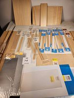 Full overview of the assortment showing balsa wood sheets, packaged sticks, styrene sheets, and wire mesh pieces laid out on a table.