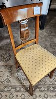 Desk chair front showing seat upholstery and carved wooden backrest lyre motif