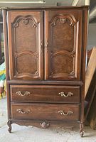 Photo of the large wooden armoire with paneled doors, brass hardware, and ornate carved accents