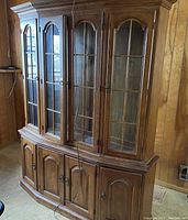 Photo of two-piece wooden China cabinet with glass-paned doors and solid lower doors.