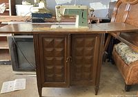 Full view of the sewing machine mounted inside the closed wooden cabinet with paneled doors