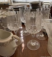 Close-up photo showing clear cut glass wine glasses with decorative faceting and white ceramic serving pot with lid in the foreground