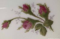 Close-up image of Rosebud pattern on china showing pink rosebuds with green leaves and delicate detailing.
