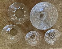 Top view of all five cut glass serving bowls arranged together on carpet, showing various sizes and cut patterns.
