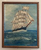 Framed oil painting of a sailing ship with multiple large white sails on a textured ocean under a cloudy sky.