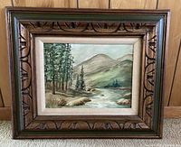 Front view of framed original painting showing woodland scene with stream and mountains, in carved wooden frame.