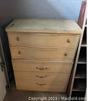Photo showing the full front view of the off-white wooden bureau with curved drawers and original hardware.