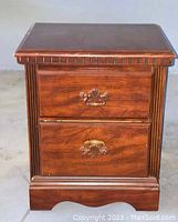 Photo of one vintage wooden night stand showing two drawers, brass handles, and carved details.