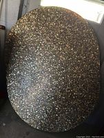 Full view of the oval resin table top embedded with crushed sea shells showing its overall shape and surface texture.