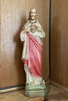 Full frontal view of painted Jesus statue on a wooden background.