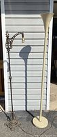 Photo showing the antique metal standing lamp with bronze detailing and the modern off-white floor lamp with flared top.