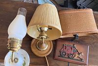 Three vintage wall sconces displayed: white ceramic with hurricane lamp, wood sconce with pleated shade, youth rustic sconce with burlap style shade and stagecoach decoration.