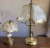 Both lamps side by side on a wooden surface with visible brass bases and glass shades