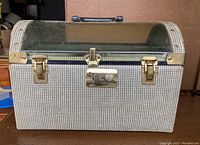 Front view of the vintage pet carrier showing the clear plastic top, metal latches, and houndstooth fabric sides.