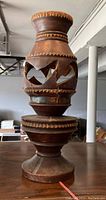 Front view of the vintage wooden tiki-style electric lamp showing carved cutouts and brown wood tone with visible cracks.