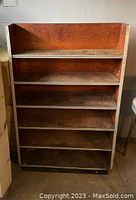 Front view of a wooden shelf unit showing five shelves with visible wear and staining on wood surfaces.