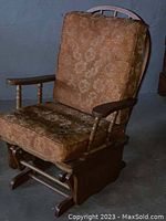 Wooden rocking chair with thick removable brown floral-pattern cushions shown from front angle.