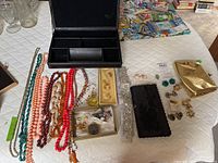 Overview of necklaces, brooches, earrings, clutches, perfume and jewelry case arranged on table