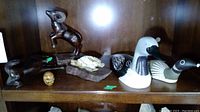 Lot displayed on wooden shelf showing a wood ram, resin turtle, wooden egg, wood and ceramic bird decoys, and a small wooden figurine.