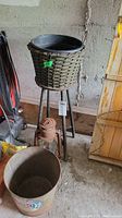 Full view of wicker planter on metal stand, rusted lantern, and metal bucket grouped together