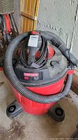 Front and angled view of red and black Craftsman shop vac with hose wrapped around top, showing brand, capacity, and motor power labels.