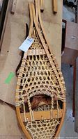 Pair of traditional wooden snowshoes showing full length and frame with rawhide webbing and binding straps.