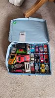 Open light blue Matchbox case containing assorted toy cars arranged inside compartments.