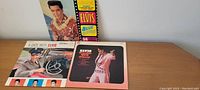 Three Elvis Presley vinyl LP records on a wooden surface, showing covers of Blue Hawaii, A Date with Elvis, and Elvis Frankie and Johnny.