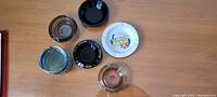 All 6 vintage ashtrays laid out on a table, showing different styles and brands including Caesar Palace and other assorted hotels.
