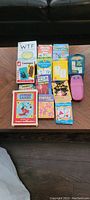 Overview of assorted kids' card games including box titles and handheld electronic game