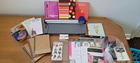 Overview of crafting supplies including notebooks, paper cutter, stickers, tape, pens, and plastic organizer.