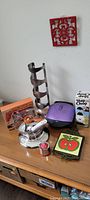 View of assorted kitchen utensils and items on wooden surface, showing metal spiral wine bottle holder, espresso maker, George Foreman grill, and other utensils