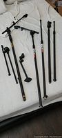 Overview of all microphone stands laid out on a bed, showing a mix of straight and boom arm stands.