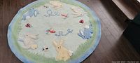 Full view of the round children's area rug showing playful bunny design and pastel colors.