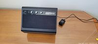 Black Singtrix multimedia speaker with knobs and attached power cord on a beige surface.