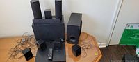 Full set of Sony surround speakers placed on a table with wires connected, showing all speakers, subwoofer, audio control unit, and remote.