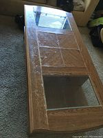 Top angled view showing wood surface with two glass panels inserted and wood panel center with symmetrical design. Visible surface wear evident.