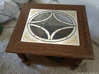 Top view showing decorative glass inset with oval motif and gold floral corner accents on a wooden frame.