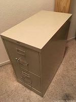 Photo of a beige metal filing cabinet with two drawers, showing front and top sides.