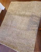 Top view of the brown shag rug laid flat on a hardwood floor showing texture, color, and size