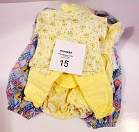 Yellow floral top, yellow pants and bloomers stacked with multi-colored patterned cloth underneath