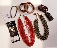 Overview of all jewelry items included in the lot: two necklaces, three bracelets, two wooden bangles, packaged earrings, and a maxsold size 50 card.