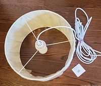 Top view of the hanging light showing the white fabric shade and bulb socket with attached electrical cord.