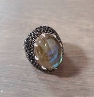 Close-up angled view of ring showing labradorite center stone and black crystal accents on band.