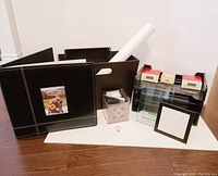 Photo showing overall lot contents including photo album, storage bins, rolled posters, office trays, and photo storage boxes.