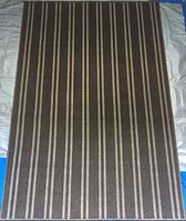 Full view of rectangular entranceway rug with vertical stripes in shades of brown and beige laid flat on ground.