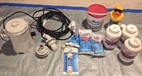Overview of pool maintenance products including pump, power cord, fittings, HTH chemical containers and packets, duck-shaped chemical dispenser, and other accessories.