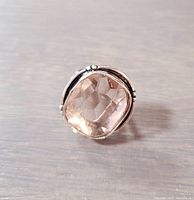 Front close-up of the silver ring showing the large light brown faceted stone in a bezel setting on a wooden surface.